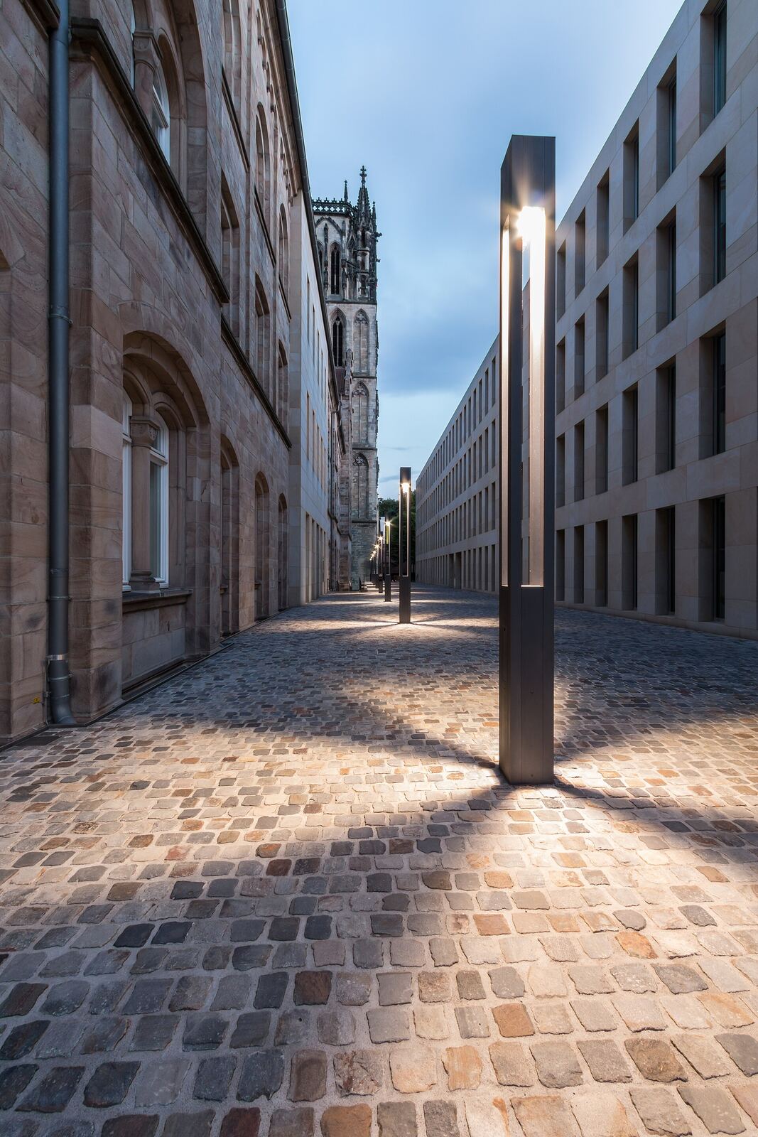 An empty cobbled street at night under a single lamp